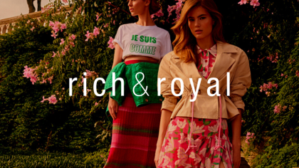 Eine Frau steht Modell in einem Feld. Sie hat modischen Kleidung der Firma Rich & Royal an und schaut zur Seite. Darüber das Logo von NETFORMIC Kunde Rich & Royal.