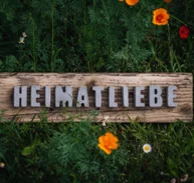 Naturholzschild "Heimatliebe" im Garten.