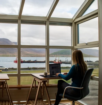 Frau arbeitet remote in einem Raum mit Panorama-Ausblick in die Natur.