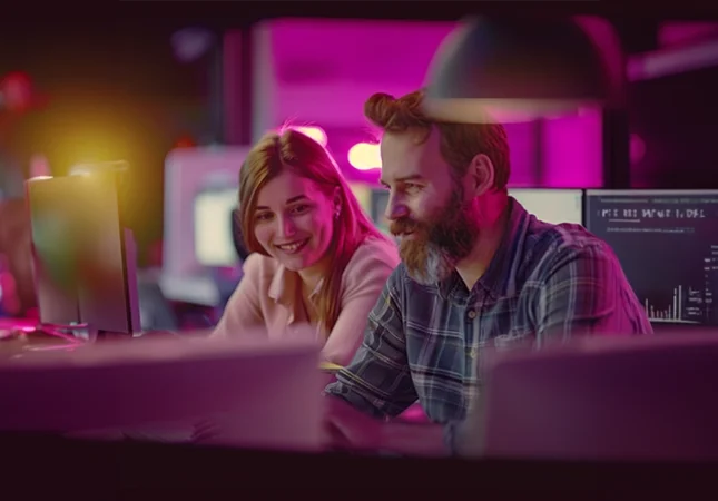 Eine Frau und ein Mann sitzen gemeinsam vor einem PC – Symbol für die effiziente Nutzung von Produktdaten und die Entwicklung individualisierter Lösungen innerhalb von Verbundgruppen.