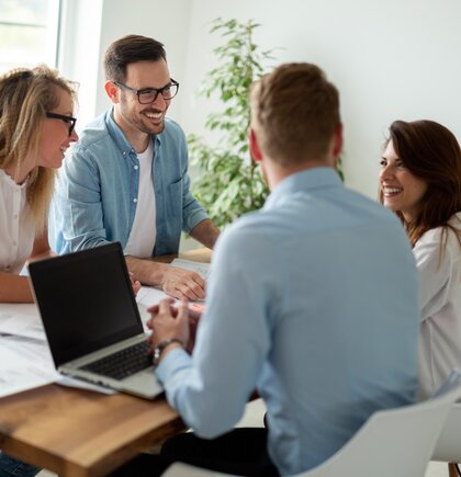 Kollegen unterhalten sich am Arbeitstisch im Büro.
