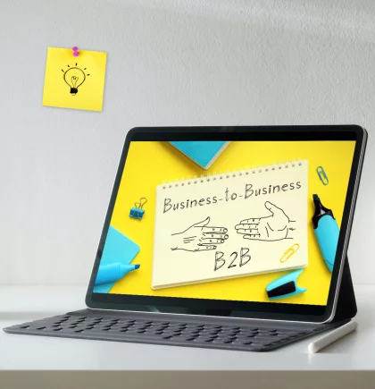 Shopware Evolve Tablet mit einem Notizblock, hellblauen Stiften im gelben Hintergrund auf dem Bildschirm. Hellgrauer Hintergrund. Ein gelber Haftnotiz mit einer Glühbirnezeichnung hängt an der Wand.