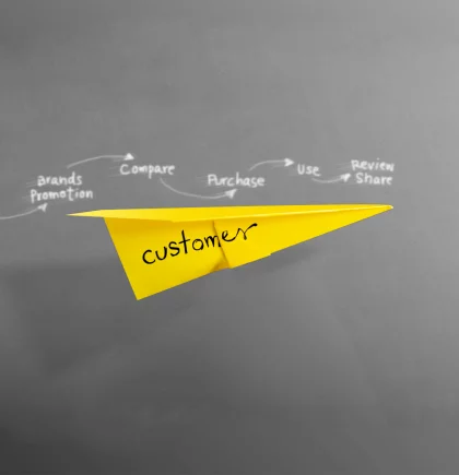 Shopware Evolve Customer Journey Ein gelber Origamiflieger auf dem dunkelgrauen Hintergrund.